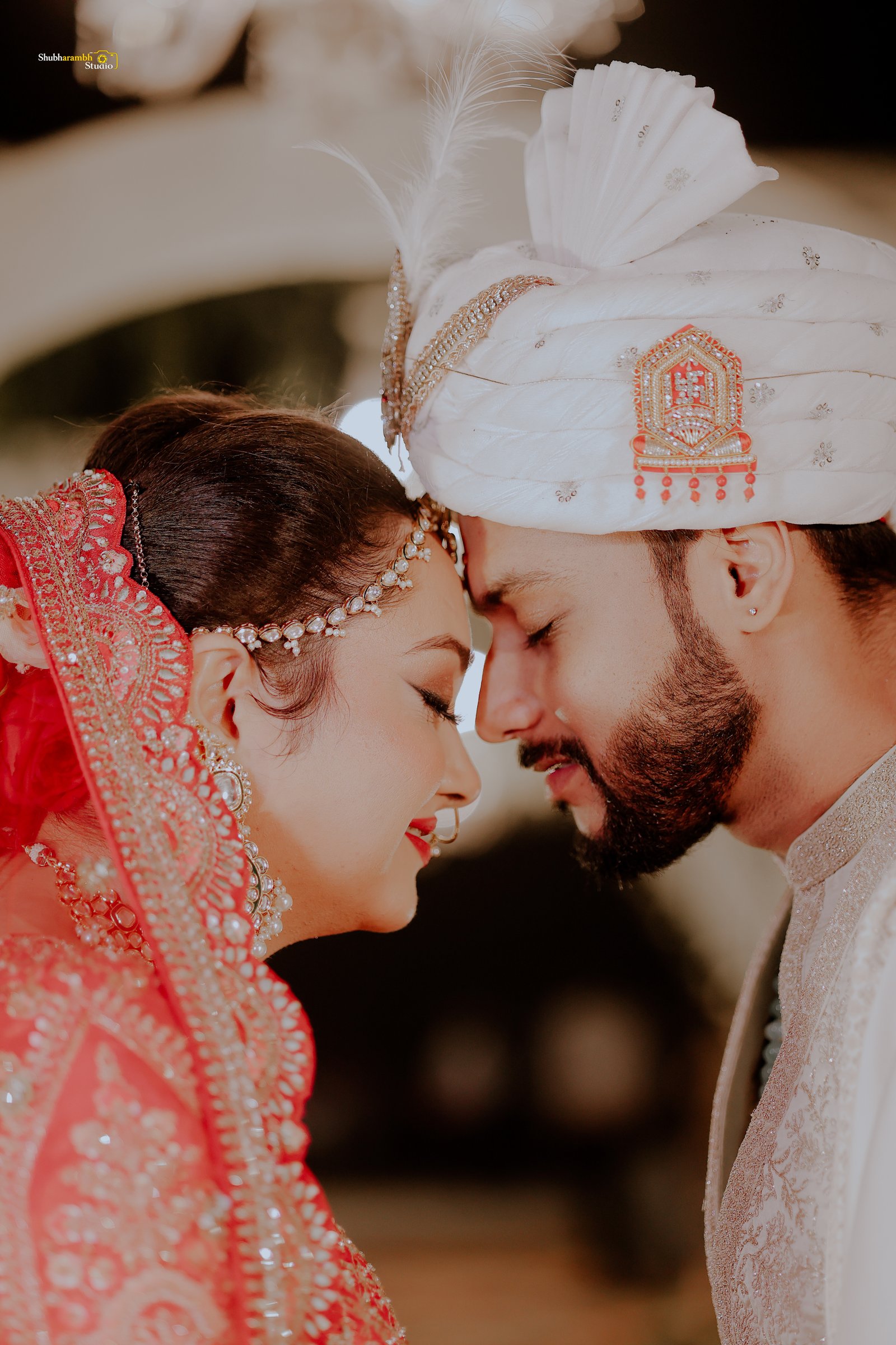 Bride smiling as she lifts her red embroidered veil